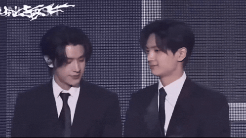 A Man In A Suit And Tie Stands Next To Another Man GIF