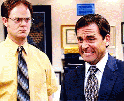 A Man In A Suit And Tie Stands Next To Another Man In A Yellow Shirt And Tie GIF