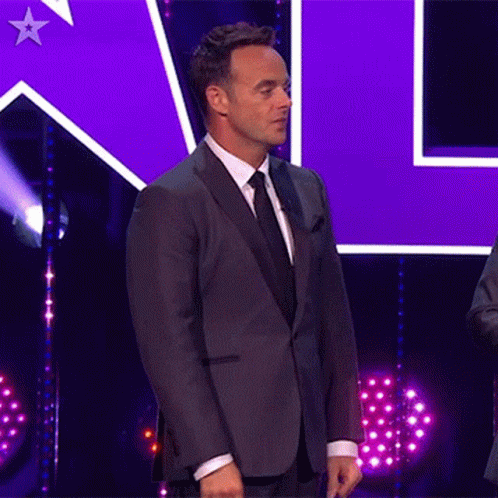 Man In Suit On Stage With Purple Star GIF