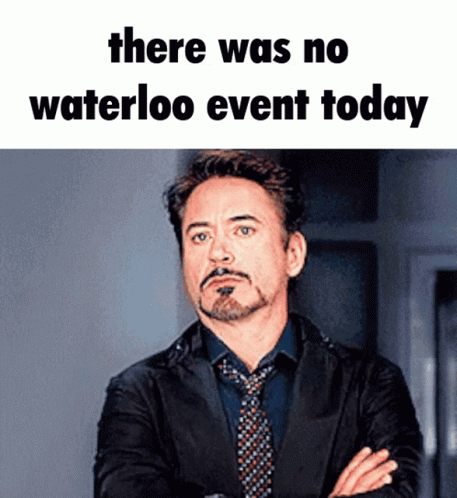 A Man In A Suit And Tie Stands With His Arms Crossed Under A Meme That Says There Was No Waterloo Event Today .. GIF