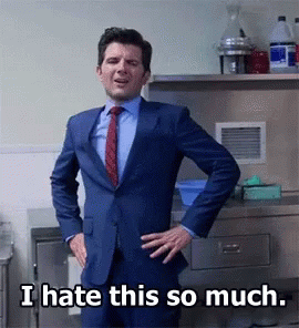 A Man In A Suit And Tie Stands With His Hands On His Hips And Says " I Hate This So Much " GIF