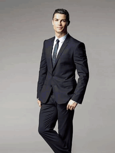 A Man In A Suit And Tie Stands With His Leg Crossed GIF