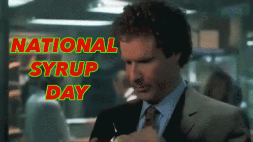 a man in a suit and tie takes a sip of syrup in front of a sign that says national syrup day