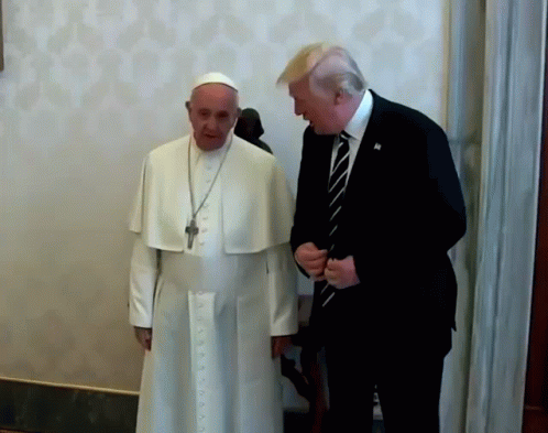 A Man In A Suit And Tie Talks To A Man In A White Robe GIF