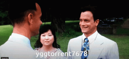 A Man In A Suit And Tie Talks To A Woman And Another Man In A White Suit GIF