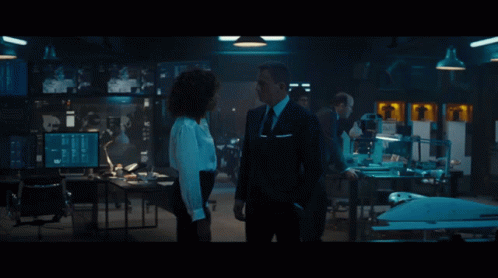 A Man In A Suit And Tie Talks To A Woman In A White Shirt GIF