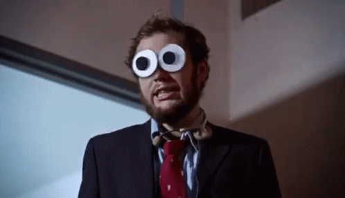 A Man In A Suit And Tie Wearing Googly Eyes GIF