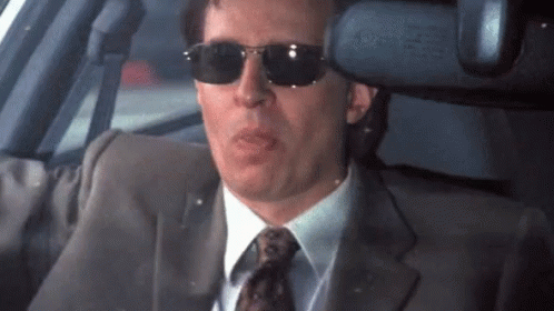 A Man In A Suit And Tie Wearing Sunglasses GIF