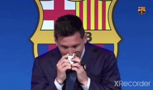 A Man In A Suit And Tie Wipes His Nose With A Napkin In Front Of A Fcb Logo GIF