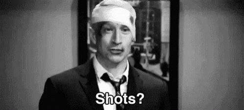 A Man In A Suit And Tie With A Bandage On His Head Is Asking Shots . GIF