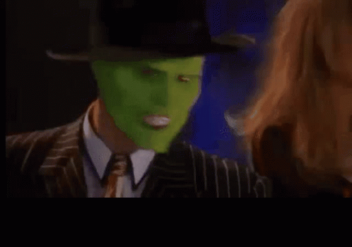 A Man In A Suit And Tie With A Green Mask On His Face Is Making A Funny Face . GIF