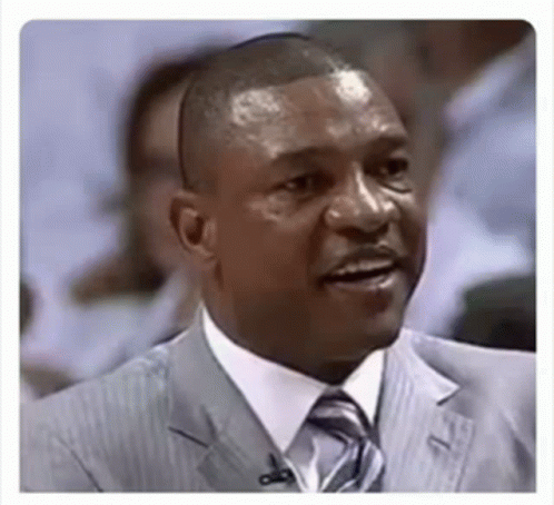 A Man In A Suit And Tie With A Microphone In His Ear Is Smiling . GIF
