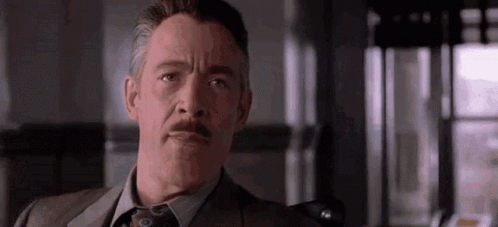 A Man In A Suit And Tie With A Mustache Is Making A Funny Face . GIF