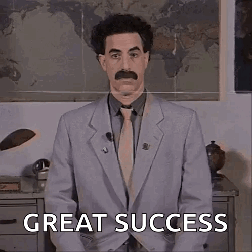 A Man In A Suit And Tie With A Mustache Is Standing In Front Of A Map And Says Great Success . GIF