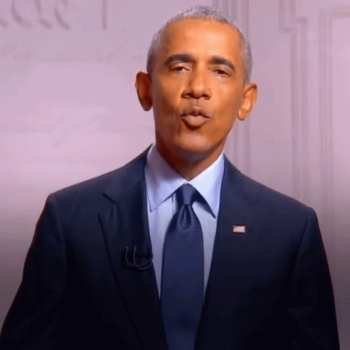 A Man In A Suit And Tie With An American Flag Pin On His Jacket GIF