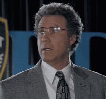 A Man In A Suit And Tie With Glasses Is Making A Funny Face . GIF