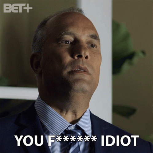 A Man In A Suit And Tie With The Words You F *** Idiot Above Him GIF