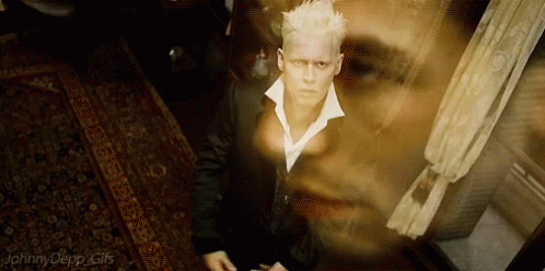 A Man In A Suit And White Collared Shirt Is Standing In A Room With A Ghost Behind Him . GIF