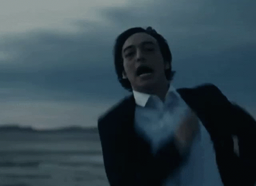 A Man In A Suit And White Shirt Is Running In The Desert With His Mouth Open . GIF