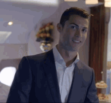 A Man In A Suit And White Shirt Is Smiling In A Room . GIF