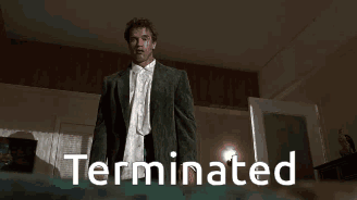 A Man In A Suit And White Shirt Is Standing In A Room With The Word Terminated On The Bottom GIF