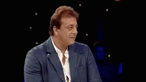 A Man In A Suit And White Shirt Is Standing In Front Of A Crowd GIF