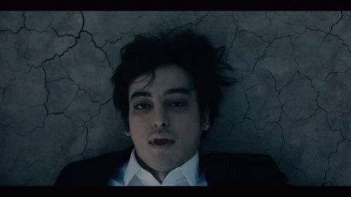 A Man In A Suit And White Shirt Laying On The Ground GIF