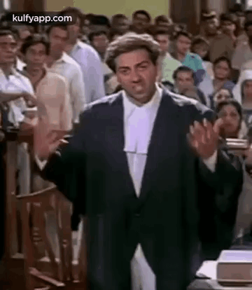 A Man In A Suit And Wig Is Giving A Speech In Front Of A Crowd Of People . GIF