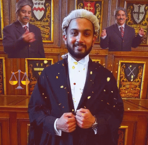 A Man In A Suit And Wig Stands In Front Of A Wall With A Coat Of Arms GIF