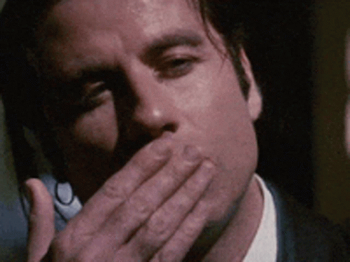 A Man In A Suit Covering His Mouth With His Hand GIF