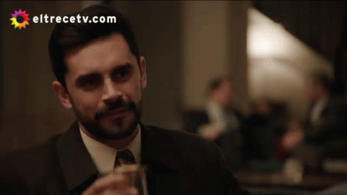 A Man In A Suit Drinking From A Glass With Eltrecetv.com Written On The Bottom GIF