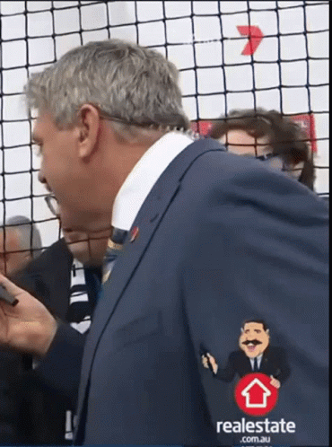 A Man In A Suit Has A Real Estate Logo On His Jacket GIF