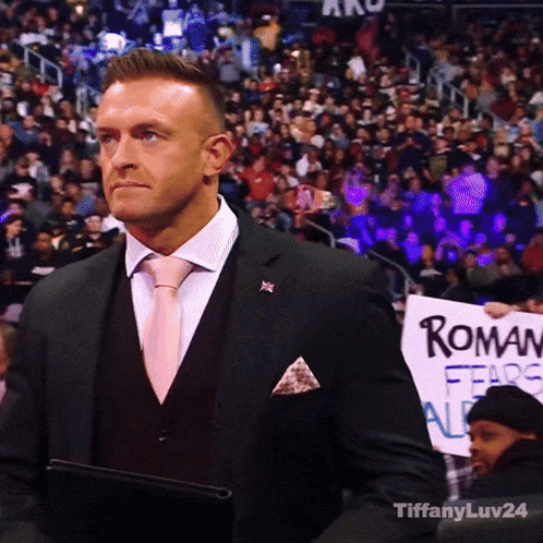 A Man In A Suit Holding A Sign That Says Roman Fears All GIF
