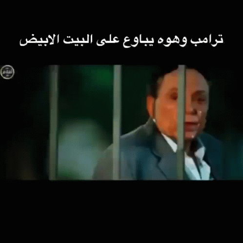 a man in a suit is behind bars with arabic writing behind him