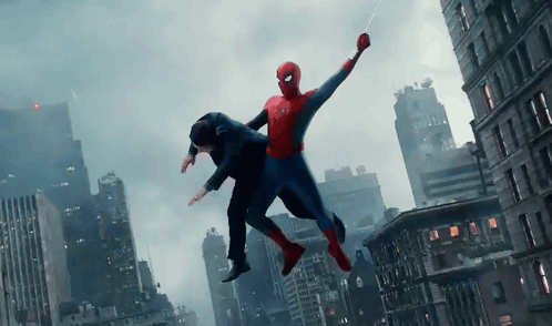 A Man In A Suit Is Being Held By A Spiderman GIF
