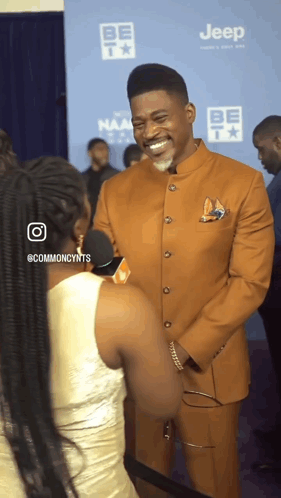 A Man In A Suit Is Being Interviewed By A Woman In Front Of A Jeep Logo GIF