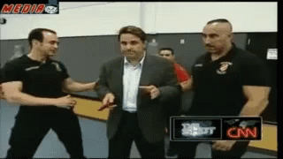 A Man In A Suit Is Being Interviewed By Two Men In Black Shirts With Cnn Written On The Bottom GIF