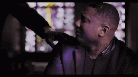 A Man In A Suit Is Being Punched In The Face By Another Man In A Dark Room . GIF