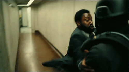 A Man In A Suit Is Being Thrown By Another Man In A Hallway . GIF