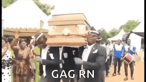 A Man In A Suit Is Carrying A Coffin In A Crowd Of People . GIF