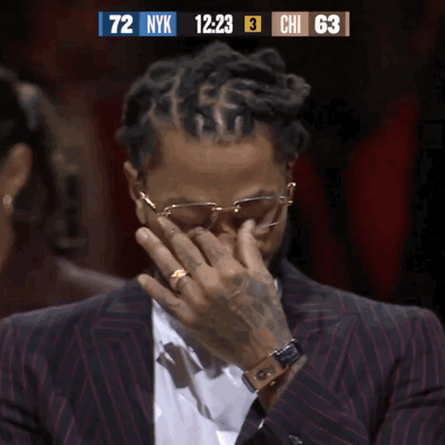 A Man In A Suit Is Covering His Face While Watching A Basketball Game GIF