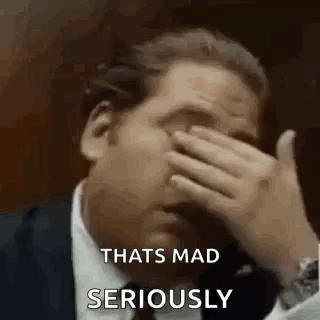 A Man In A Suit Is Covering His Face With His Hand And Saying `` That 'S Mad Seriously '' . GIF