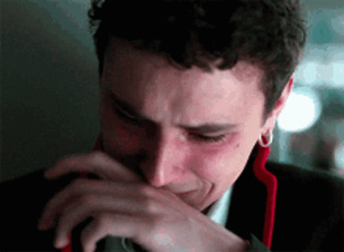 A Man In A Suit Is Crying And Covering His Mouth With His Hand . GIF