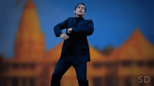 A Man In A Suit Is Dancing In Front Of A Building With The Letters Sd On The Bottom GIF