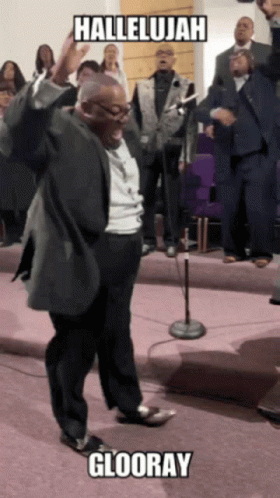A Man In A Suit Is Dancing In Front Of A Choir With The Words Hallelujah Glooray Written Above Him GIF