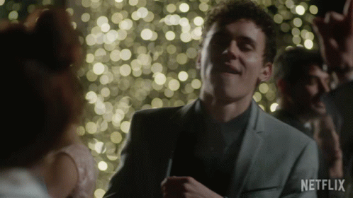 A Man In A Suit Is Dancing In Front Of A Crowd With A Netflix Logo In The Corner GIF