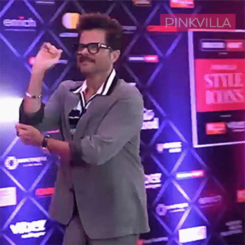 A Man In A Suit Is Dancing In Front Of A Pinkvilla Sign GIF