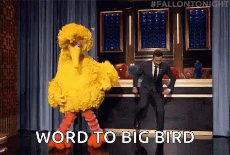 A Man In A Suit Is Dancing Next To A Big Bird Costume . GIF