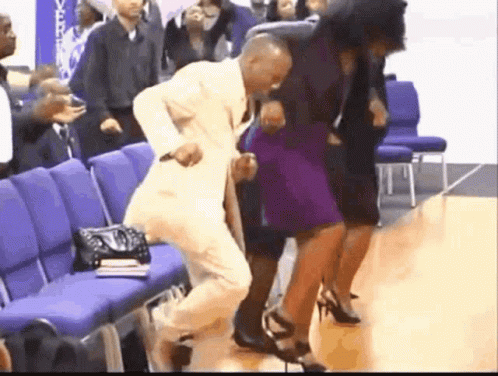 A Man In A Suit Is Dancing With A Woman In A Purple Dress In A Church . GIF