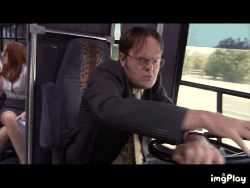 A Man In A Suit Is Driving A Bus With A Woman Sitting In The Back Seat GIF